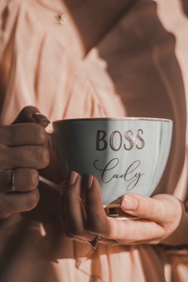 a woman holding a white cup with boss lady written on it